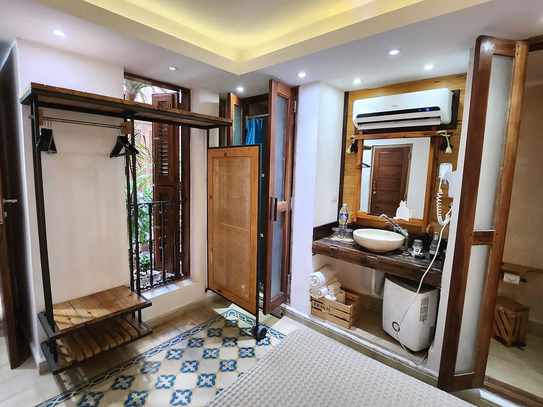 Standard room showing the bed, patterned floor, handcrafted woodwork, and movable privacy screen